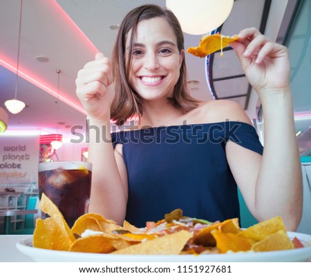 young pretty woman having a cheese nachos plate