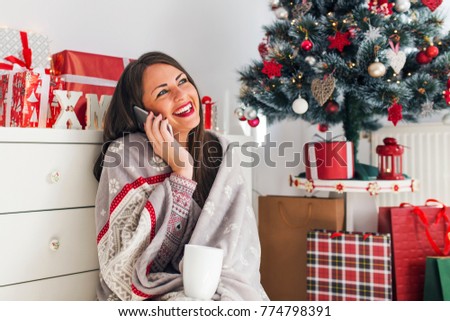 Young pretty woman having phone call next to Christmas tree