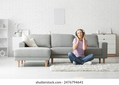 Young pretty woman in headphones listening music on floor in stylish living room - Powered by Shutterstock