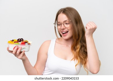 Young Pretty Woman Holding A Bowl Of Fruit Isolated On White Background Celebrating A Victory