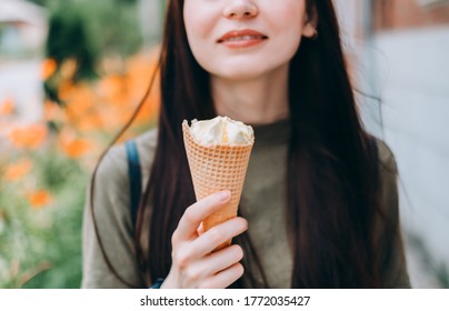 Young Pretty Woman Holding Ice Cream In A Waffle Cone While Walking Along The Street In The Park Alone.