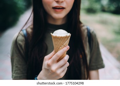 Young Pretty Woman Holding Ice Cream In A Waffle Cone While Walking Along The Street In The Park Alone.