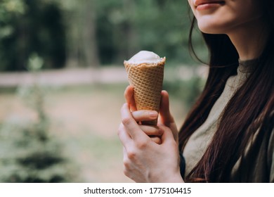 Young Pretty Woman Holding Ice Cream In A Waffle Cone While Walking Along The Street In The Park Alone.