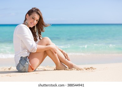 Young Pretty Woman In Hot Pants Is Sitting At Beach