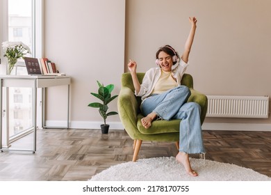 Young pretty woman listening music in headphones . Full view of funny caucasian woman having fun at home sitting on green chair. Concept of use technology  - Shutterstock ID 2178170755