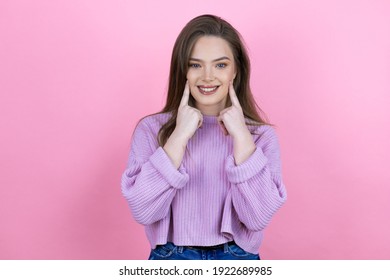 Young pretty woman with long hair standing over isolated pink background smiling confident showing and pointing with fingers teeth and mouth