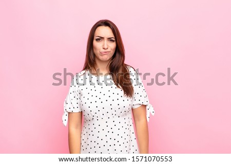 young pretty woman looking goofy and funny with a silly cross-eyed expression, joking and fooling around against pink wall