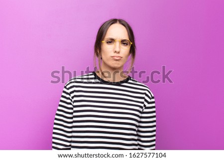 young pretty woman looking goofy and funny with a silly cross-eyed expression, joking and fooling around against purple wall