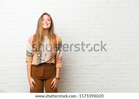 young pretty woman looking happy and goofy with a broad, fun, loony smile and eyes wide open