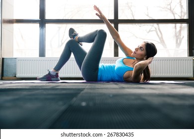 Young pretty woman lying on the yoga mat and doing exercise at gym: zdjęcie stockowe