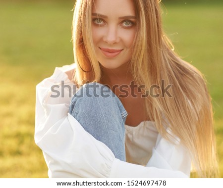 Young pretty woman natural outdoor portrait. Young pretty woman natural outdoor portrait. Beautiful girl sitting at grass at sunset