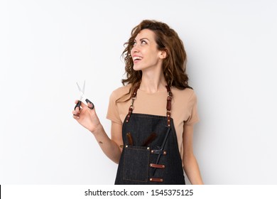 Young pretty woman over isolated background with hairdresser or barber dress looking up