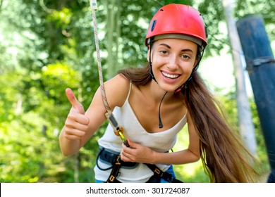 Young and pretty woman in red helmet riding on a zip line in the forest. Active sports kind of recreation - Powered by Shutterstock