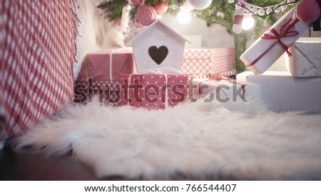 Young pretty woman in red high-heeled shoes puts Christmas present under a Christmas tree. Close up view legs