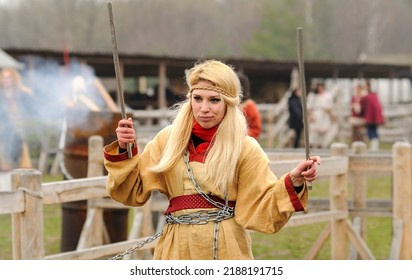 Young Pretty Woman Reenactor Dressed Like Medieval Slavonic Girl Dancing With Sticks, Pagan Dance. April 7, 2012. Kyiv Rus Park, Ukraine