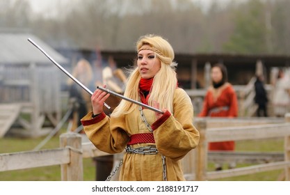 Young Pretty Woman Reenactor Dressed Like Medieval Slavonic Girl Dancing With Sticks, Pagan Dance. April 7, 2012. Kyiv Rus Park, Ukraine