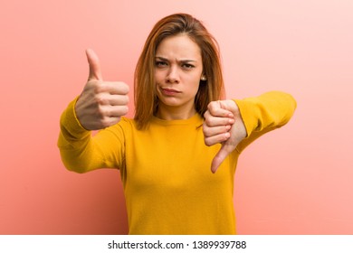 Young Pretty Young Woman Showing Thumbs Up And Thumbs Down, Difficult Choose Concept