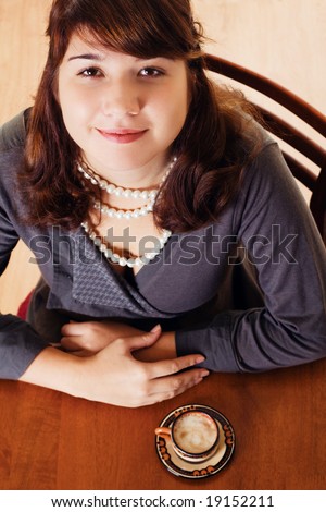 Young pretty woman sitting by the table with coffee