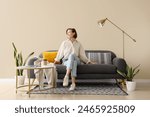 Young pretty woman sitting on sofa in light living room