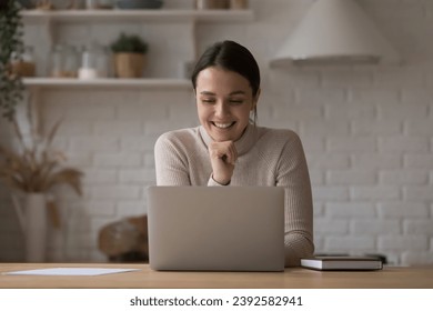 Young pretty woman smile use laptop spend time alone in kitchen. Happy e-commerce client makes order, buy goods, food via comfy e-services for comfort life. Modern tech, telecommute, leisure concept
