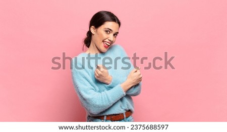 young pretty woman smiling cheerfully and celebrating, with fists clenched and arms crossed, feeling happy and positive