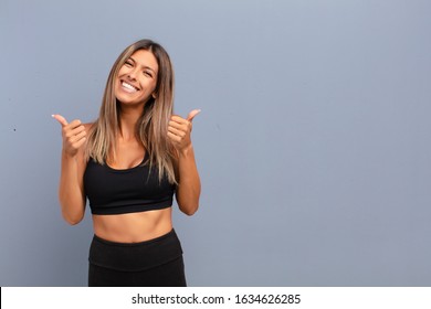 Young Pretty Woman Smiling Joyfully And Looking Happy, Feeling Carefree And Positive With Both Thumbs Up