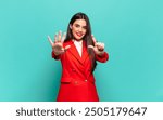 young pretty woman smiling and looking friendly, showing number seven or seventh with hand forward, counting down. business concept