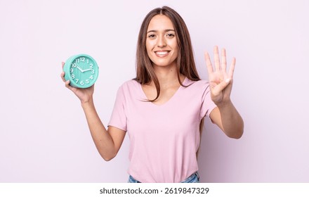 young pretty woman smiling and looking friendly, showing number four. alarm clock concept - Powered by Shutterstock - Get 15% off with code: PIKWIZARD15