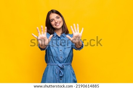 young pretty woman smiling and looking friendly, showing number ten or tenth with hand forward, counting down