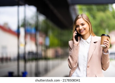 Young pretty woman talking on the smartphone drinking coffee at street - Shutterstock ID 2178508341