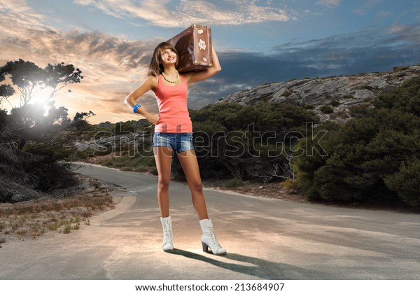 Young pretty woman tourist with suitcase with\
suitcase on shoulder