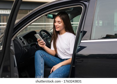 Young pretty woman use phone while sitting in her new car - Powered by Shutterstock