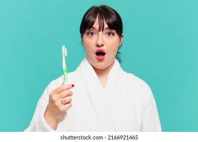 young pretty woman wearing bathrobe scared expression and a teethbrush - Powered by Shutterstock