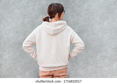 Young pretty woman in white hoodie. Back view, mock up. Copy space.