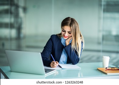 Young Pretty Woman Working With Laptop And Taking Notes On A Desktop At Office