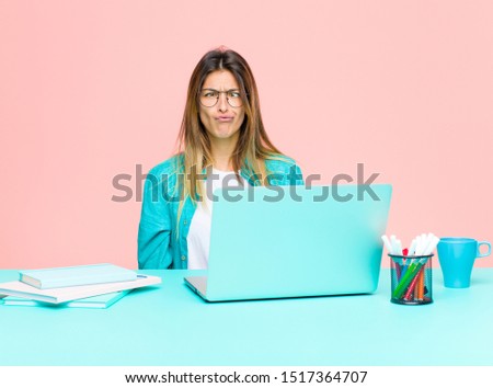 young pretty woman working with a laptop looking goofy and funny with a silly cross-eyed expression, joking and fooling around