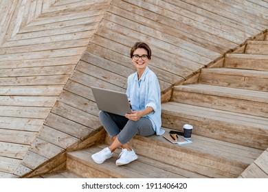 Young Pretty Woman Working On Laptop In IT Outside In Modern Park Street Sitting On Remote Work, Summer Style Casual Smiling Wearing Glasses