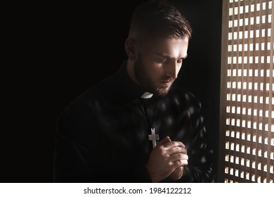 Young priest in confession booth
