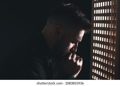 Young priest in confession booth