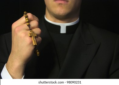 Young Priest Praying With Rosary In Hand