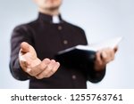 Young priest reading the Holy Bible and stretching his hand on neutral background