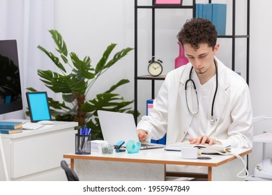 A Young Primary Care Physician Enters Patient Data Into A Laptop Database. Doctor's Office