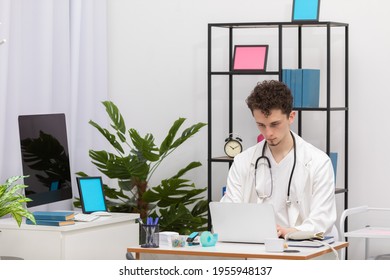 A Young Primary Care Physician Enters Patient Data Into A Laptop Database. Doctor's Office