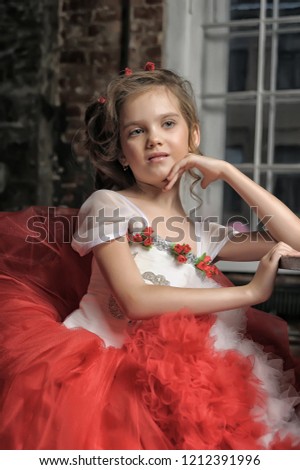 young princess in a red and white dress sitting by the table