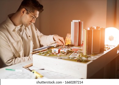 young professional architect in glasses designs landscape around buildings in the light room.close up side view photo - Powered by Shutterstock