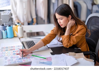 Young professional clothes fashion designer sitting near sewing machine use laptop computer   tablet pc to reference   draw the design the paper pattern