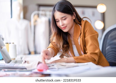 Young professional clothes fashion designer sitting near sewing machine use laptop computer   tablet pc to reference   concentrate her work pattern