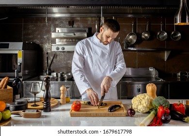 young professional cook man cut fresh vegetables in kitchen, he is cooking delicious garnish for clients in restaurant. culinary concept - Powered by Shutterstock