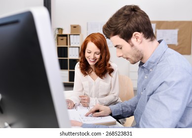 Young Professional Couple Sitting At The Office Table While Discussing Projects With Documents
