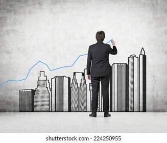 Young Professional Drawing A Growing Real Estate Chart. Concrete Background. 